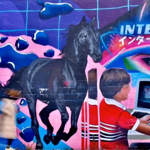 A blurred person walking across a colourful retro mural